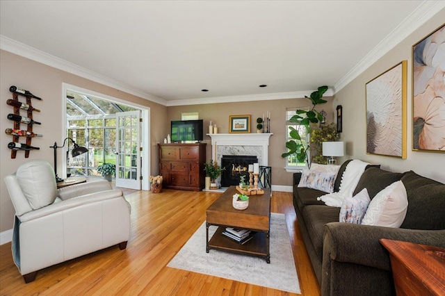 living area with ornamental molding, a fireplace, and light wood-style flooring