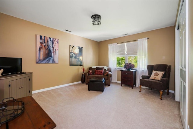 living area with light colored carpet, baseboards, and visible vents