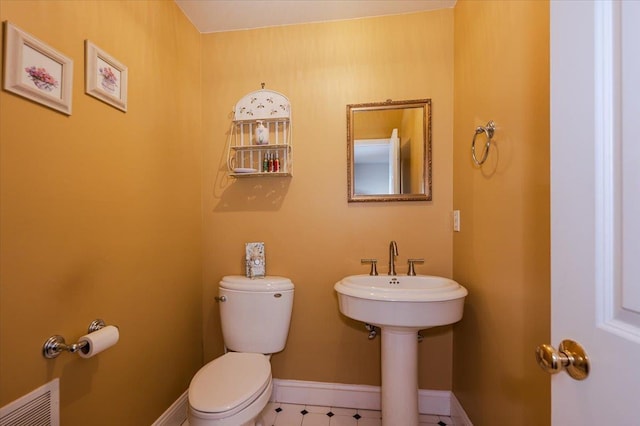 half bathroom featuring baseboards, toilet, and visible vents