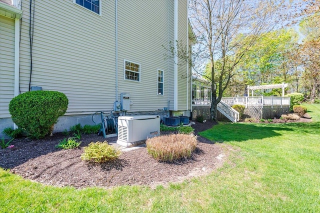 view of side of property with a lawn, a wooden deck, and stairway