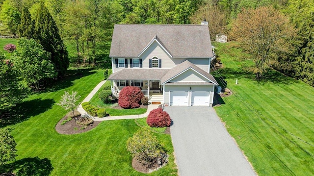 view of front of home with covered porch, a chimney, driveway, and a front lawn
