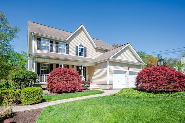 view of front of property featuring covered porch, a front yard, and a garage