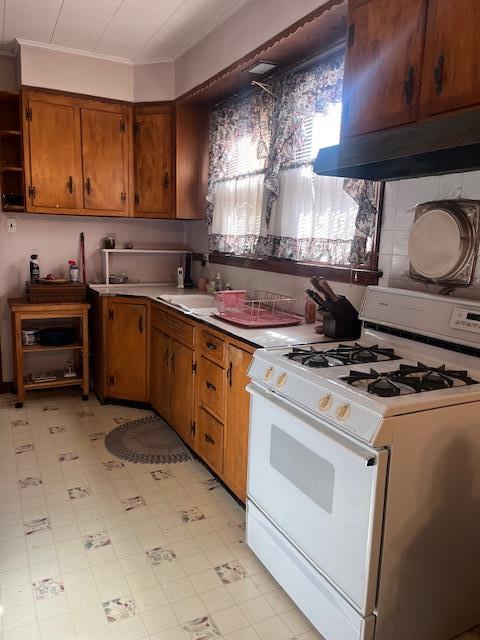 kitchen with open shelves, a sink, under cabinet range hood, brown cabinetry, and white range with gas cooktop