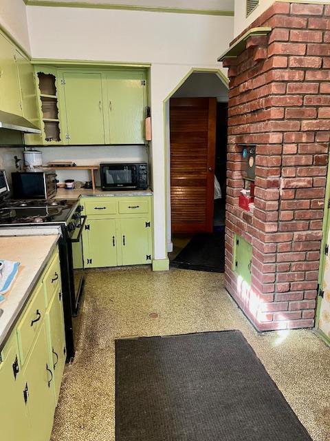 kitchen with green cabinets, light countertops, open shelves, and black appliances