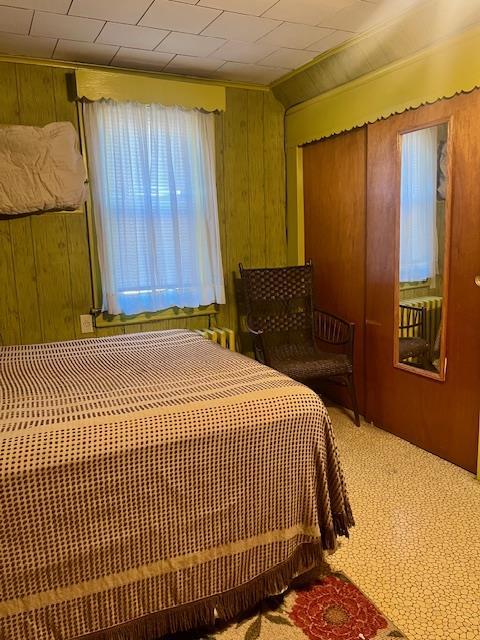carpeted bedroom with ornamental molding and wood walls
