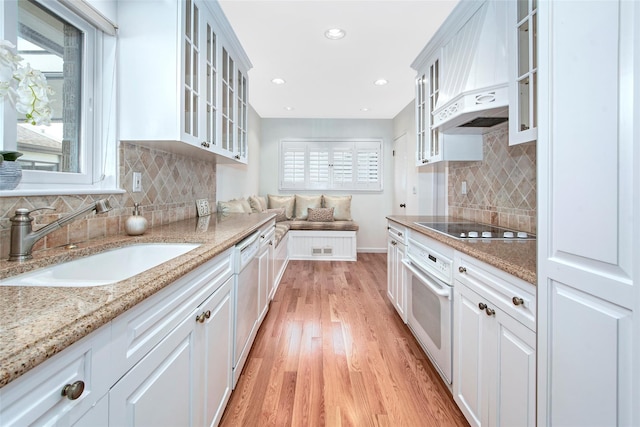 55 Waters Edge Unit 55, Rye, NY 10580 - kitchen featuring white appliances, custom exhaust hood, light wood-type flooring, decorative backsplash, and white cabinetry