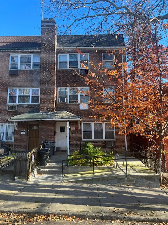 multi unit property featuring a chimney, brick siding, and a fenced front yard