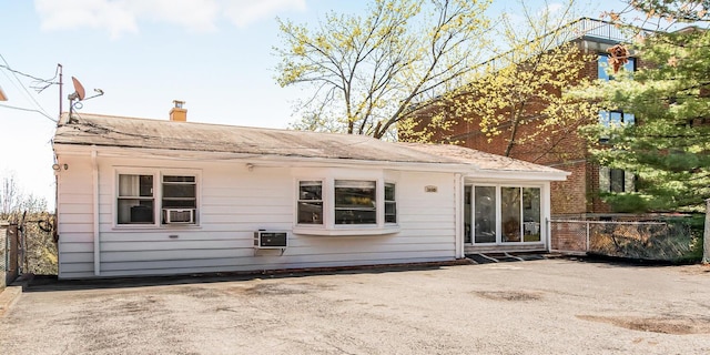 rear view of property featuring a chimney, fence, and roof with shingles