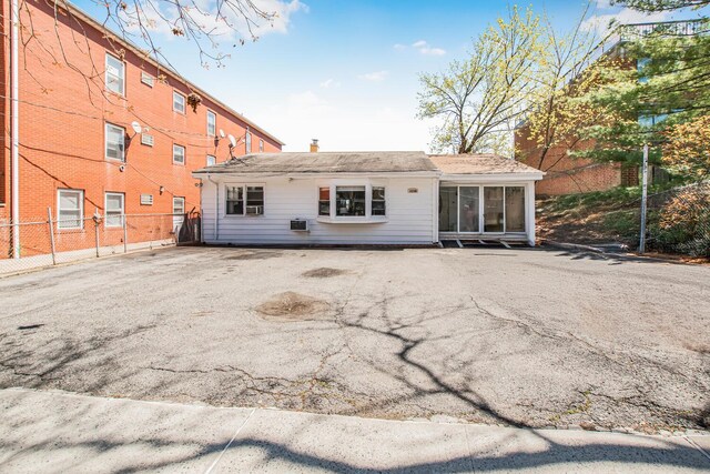 rear view of property featuring a sunroom, a chimney, and fence