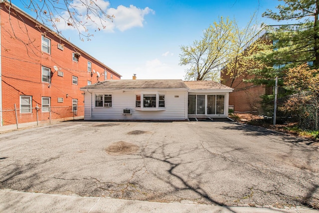 back of property with fence, driveway, a chimney, and a sunroom