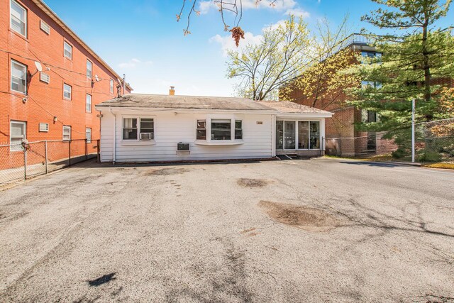 back of property featuring a chimney, fence, and a sunroom