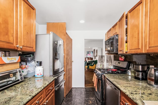 kitchen with appliances with stainless steel finishes, granite finish floor, light stone counters, and glass insert cabinets