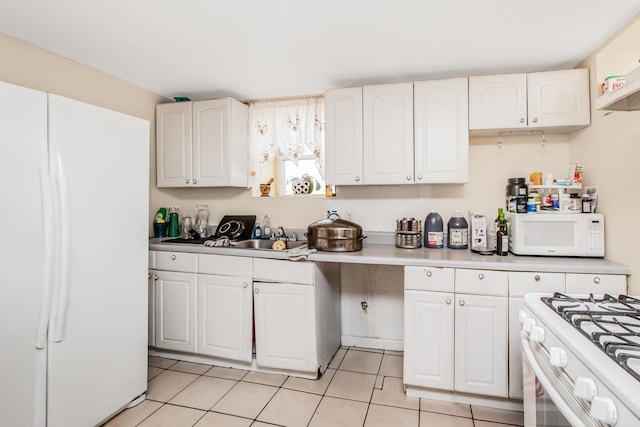 kitchen with light tile patterned flooring, a sink, white cabinetry, and white appliances