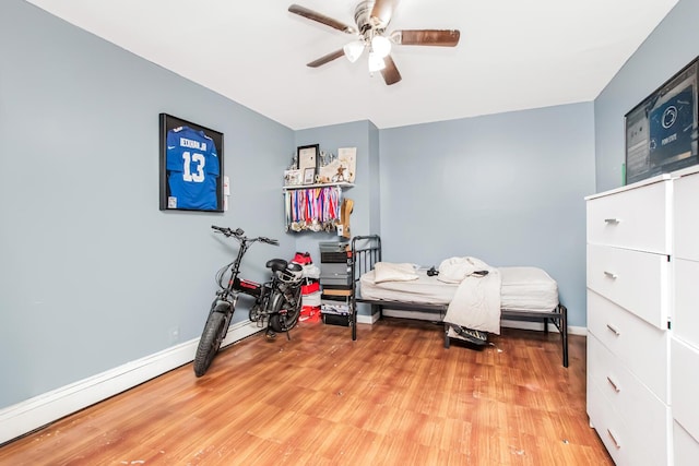 bedroom with light wood finished floors, baseboards, and ceiling fan