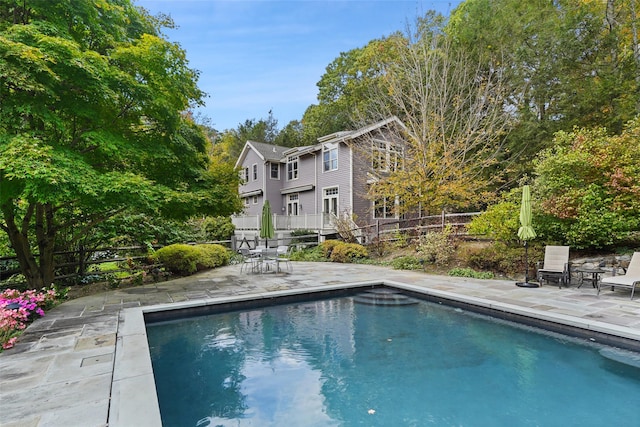 outdoor pool with a patio and fence