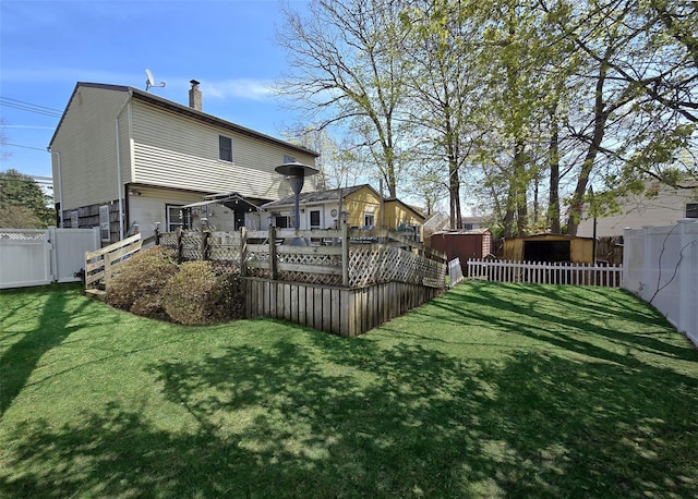 rear view of property with a chimney, a fenced backyard, a shed, and a yard