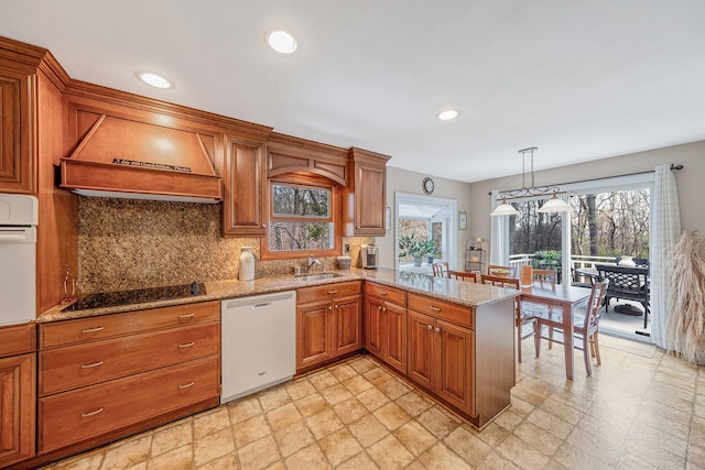 kitchen featuring white appliances, a sink, premium range hood, brown cabinets, and backsplash