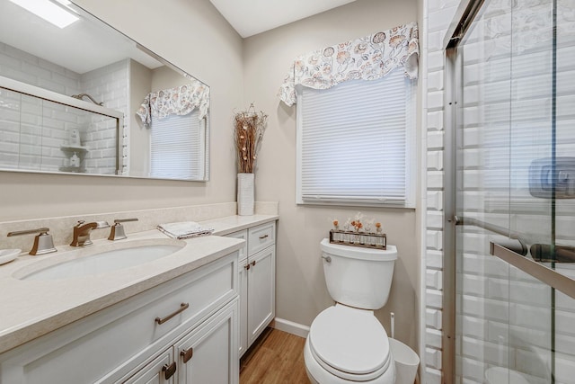 bathroom featuring baseboards, toilet, vanity, wood finished floors, and a stall shower