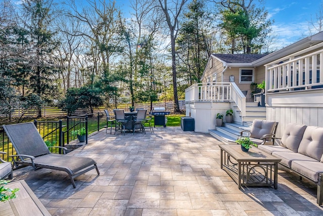 view of patio with a grill, fence, stairway, outdoor dining space, and an outdoor living space