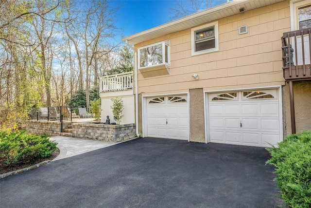 view of home's exterior with an attached garage, aphalt driveway, and a balcony