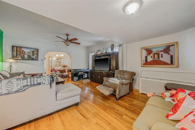 living room featuring light wood-type flooring and ceiling fan with notable chandelier