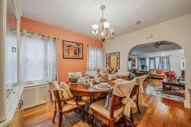 dining room with plenty of natural light, arched walkways, and wood-type flooring