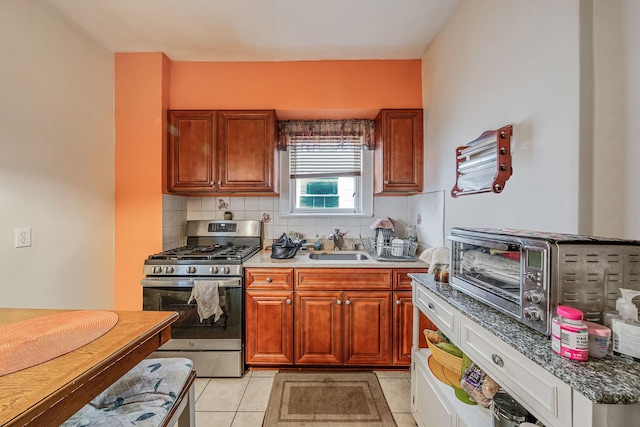 kitchen featuring a sink, a toaster, backsplash, and stainless steel gas range oven