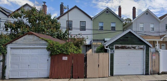 view of front of house featuring a detached garage, a chimney, and fence