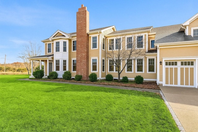 view of front of property featuring concrete driveway, a front lawn, an attached garage, and a chimney