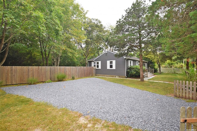 exterior space featuring gravel driveway, fence private yard, and a lawn