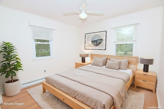 bedroom featuring light wood-style flooring, a baseboard radiator, and crown molding