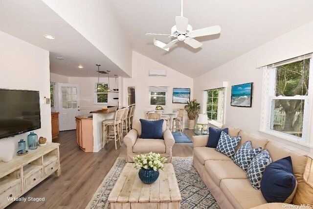 living room with a wealth of natural light, high vaulted ceiling, a ceiling fan, and wood finished floors