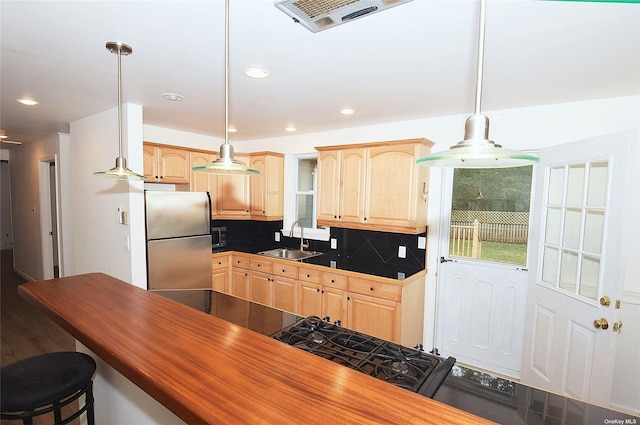 kitchen featuring light brown cabinets, freestanding refrigerator, a sink, and dark countertops