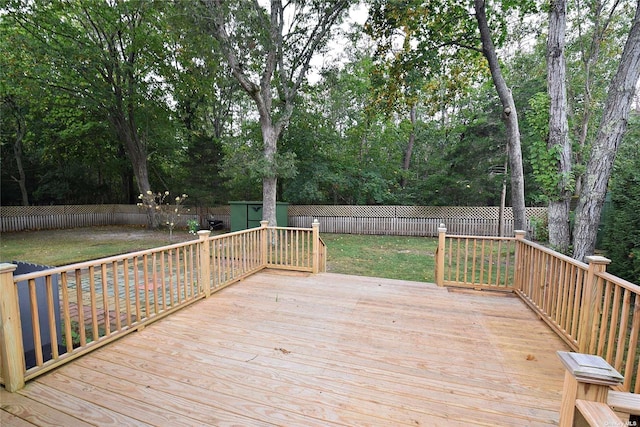 deck featuring a shed, a yard, a fenced backyard, and an outdoor structure