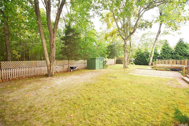 view of yard with an outbuilding, a fenced backyard, a wooden deck, and a storage shed