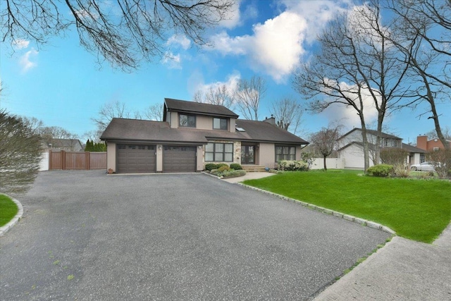 prairie-style home featuring aphalt driveway, a garage, fence, and a front lawn