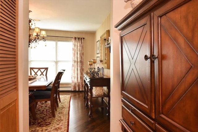 interior space with dark wood-style flooring, a notable chandelier, and baseboard heating