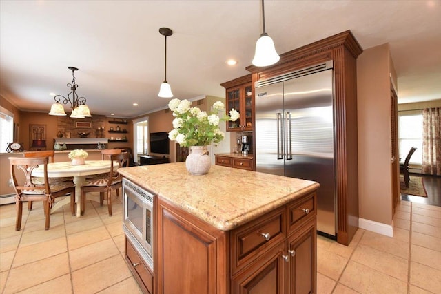 kitchen with pendant lighting, a healthy amount of sunlight, built in appliances, and light tile patterned floors
