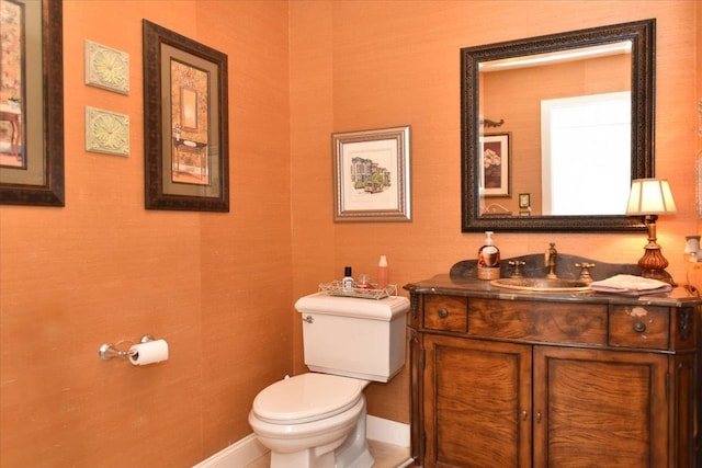 half bathroom featuring vanity, baseboards, and toilet