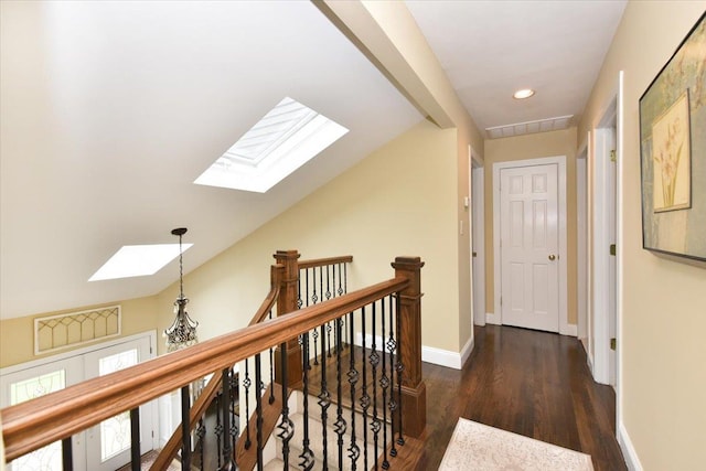 corridor featuring vaulted ceiling with skylight, recessed lighting, wood finished floors, an upstairs landing, and baseboards