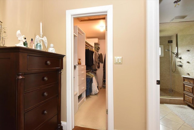 interior space with tile patterned floors, a walk in closet, and a stall shower