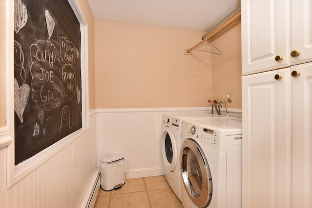 clothes washing area featuring light tile patterned floors, a baseboard radiator, independent washer and dryer, wainscoting, and cabinet space