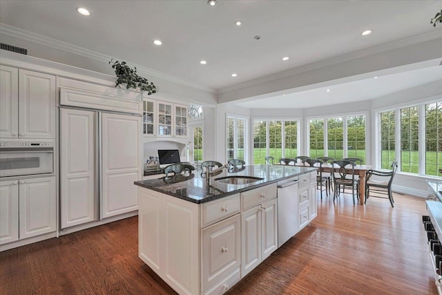 30 Morris Ln, Scarsdale, NY 10583 - kitchen featuring stainless steel dishwasher, a center island with sink, white oven, wood finished floors, and crown molding