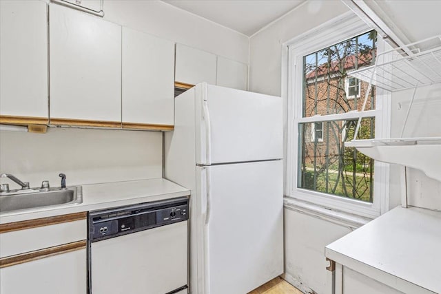 kitchen with a sink, light countertops, white appliances, and white cabinetry