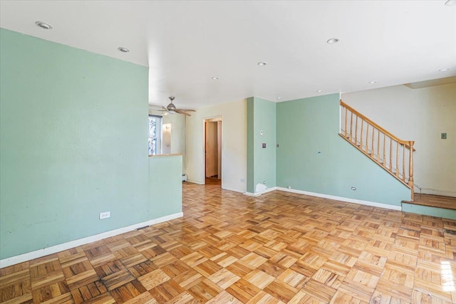unfurnished living room with stairs, baseboards, and ceiling fan