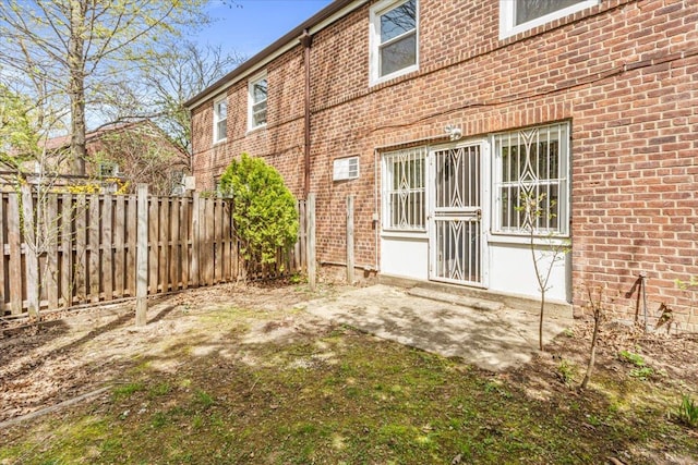 exterior space featuring brick siding, fence, and a patio