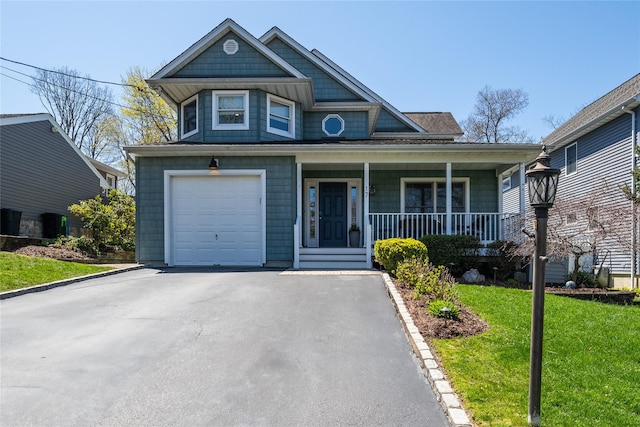 view of front of property featuring a porch, an attached garage, driveway, and a front yard