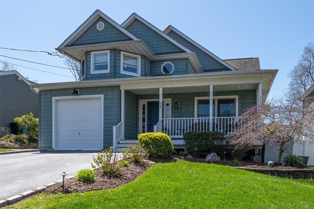 view of front facade featuring driveway, a garage, a front yard, and covered porch