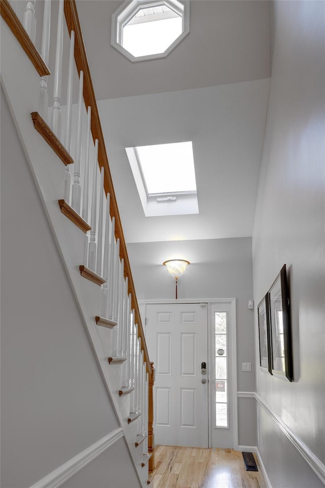entrance foyer with a skylight, light wood-style floors, and stairway