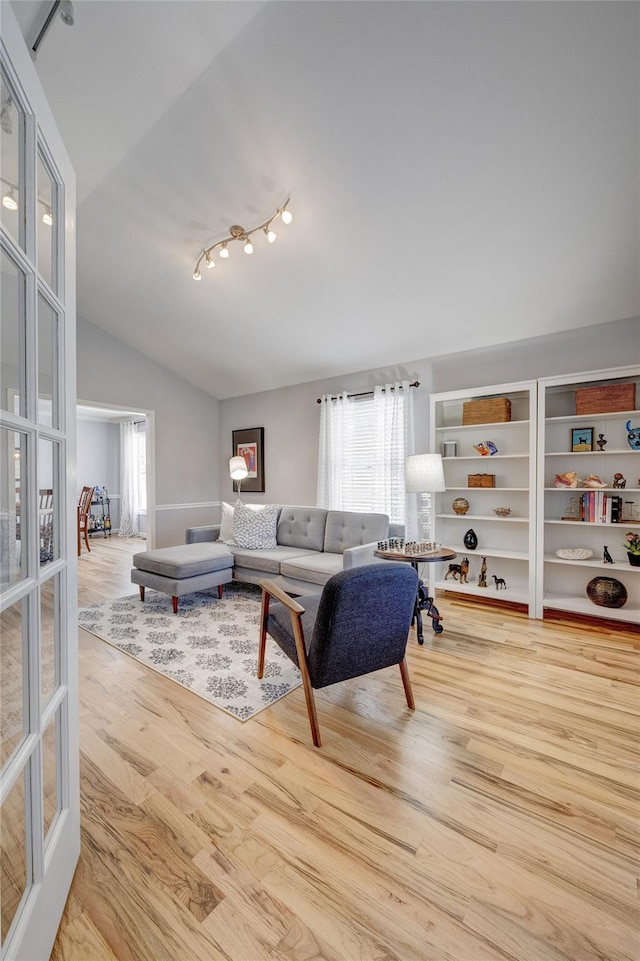 living room with rail lighting, lofted ceiling, a healthy amount of sunlight, and wood finished floors